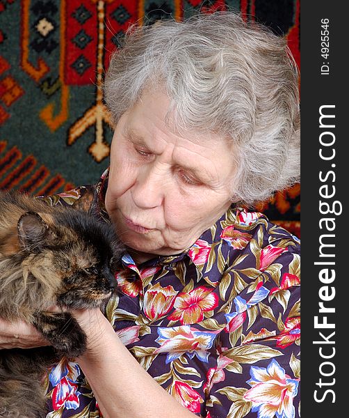 Grandmother with cat on her hands at home