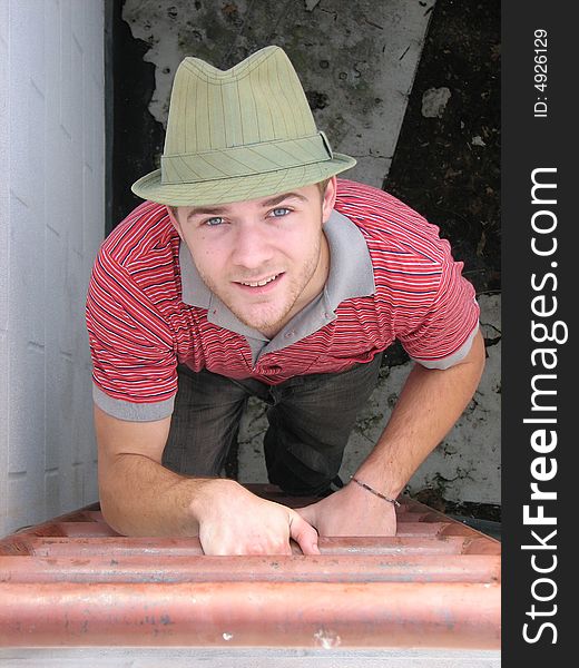 A young man climbing a rooftop ladder.  The shot is taken from the top looking down. A young man climbing a rooftop ladder.  The shot is taken from the top looking down.