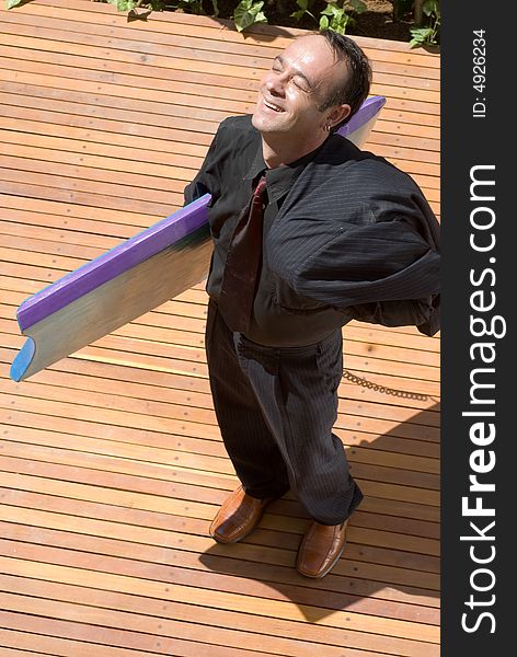 A businessman in a black pinstripe suit, holding a body board, looking up in relief that the day is over. A businessman in a black pinstripe suit, holding a body board, looking up in relief that the day is over..