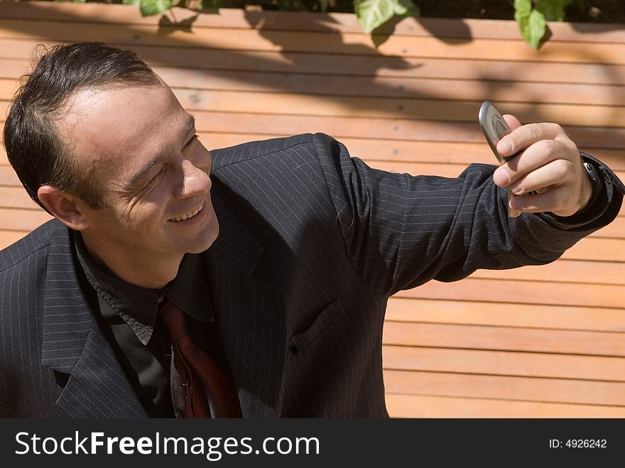 A businessman in a black pinstripe suit checking his cellphone's caller id. A businessman in a black pinstripe suit checking his cellphone's caller id.