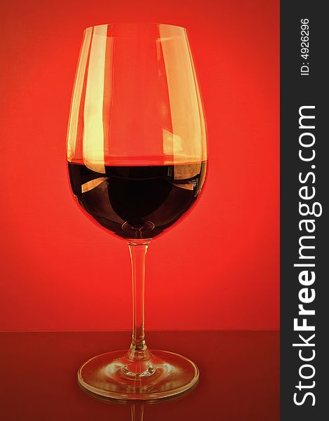 A glass of red wine isolated against a red background