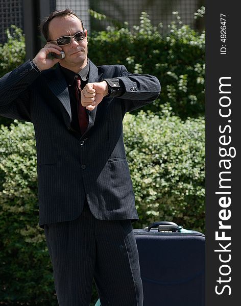 Latin american businessman checking his watch while on his cell phone. Latin american businessman checking his watch while on his cell phone