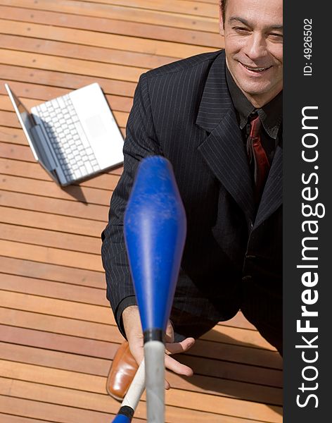 A businessman standing next to silver laptop juggling. A businessman standing next to silver laptop juggling.