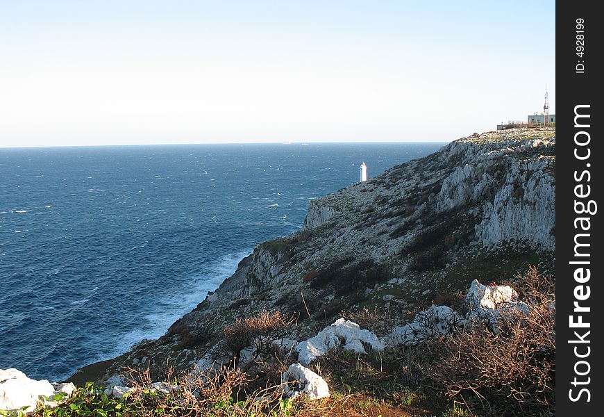 Cliff with a lighthouse in the distance. Cliff with a lighthouse in the distance