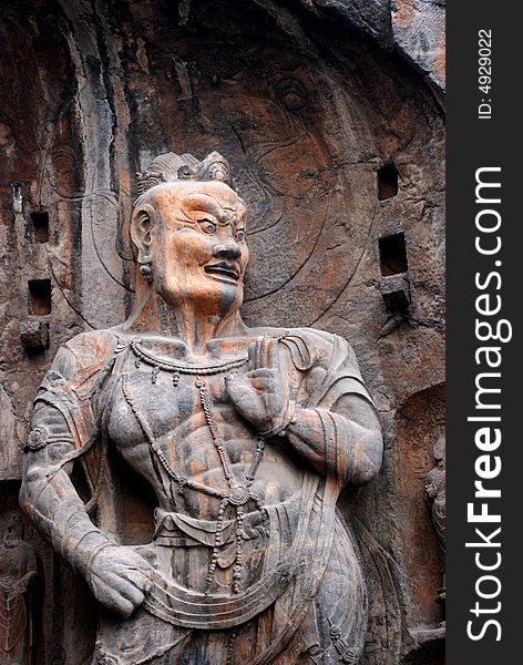 A stone statue of the Vajra, warrior of the Buddhism,chiseled out of the mountain side,Longmen Grottos,Luoyang,Henan,China.