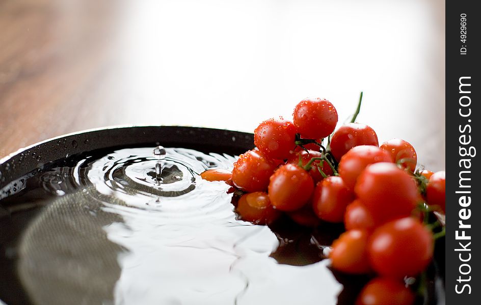 Tomato-cherry in the bowl full of fresh water / drop. Tomato-cherry in the bowl full of fresh water / drop