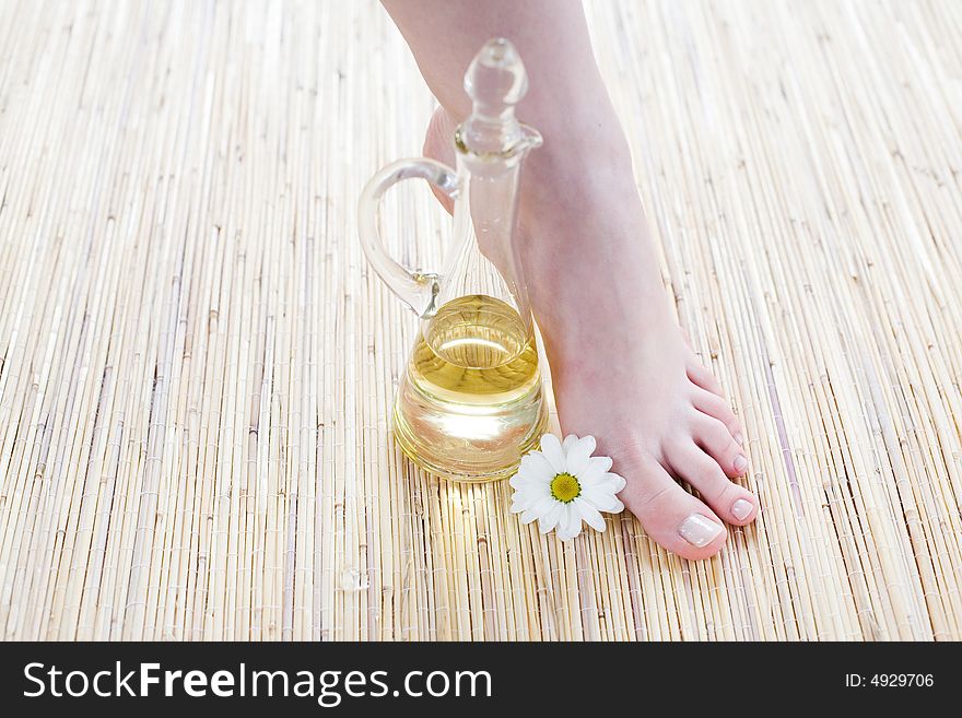 Foot care -Spa and wellness scene - Feet and oil on the bamboo mat. Foot care -Spa and wellness scene - Feet and oil on the bamboo mat