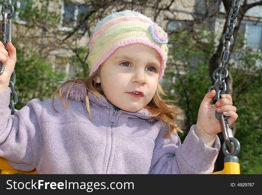 Little sweet girl is swinging on a playground. Little sweet girl is swinging on a playground