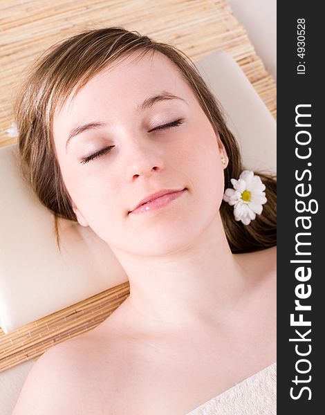Portrait of fresh and beautiful young woman laying on bamboo mat / taking spa treatment. Portrait of fresh and beautiful young woman laying on bamboo mat / taking spa treatment