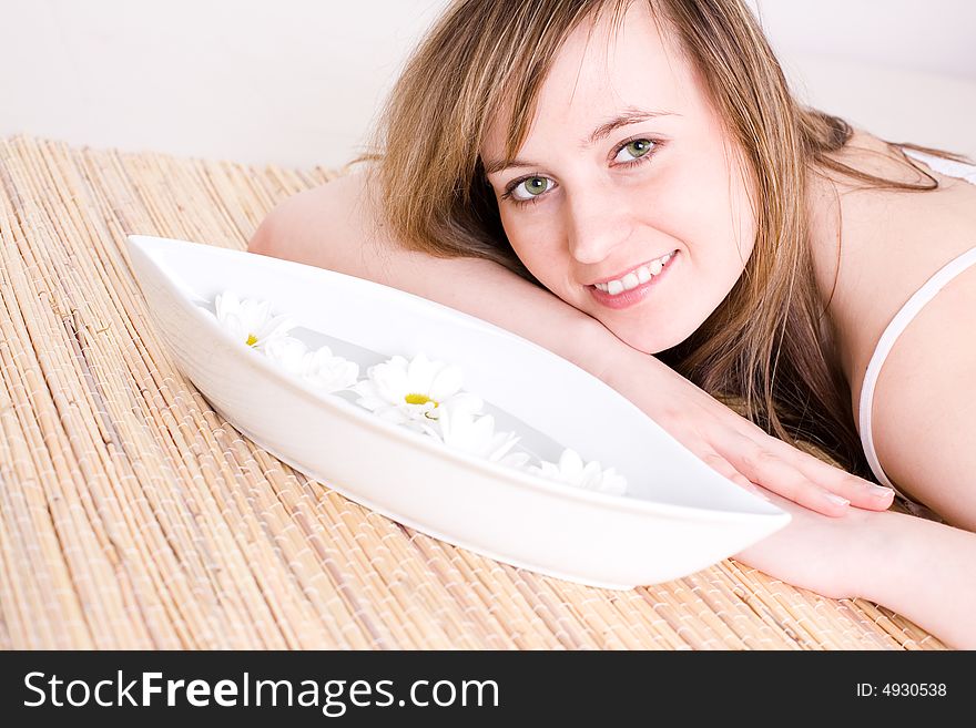 Portrait of fresh and beautiful young woman laying on bamboo mat / taking spa treatment / aromatherapy. Portrait of fresh and beautiful young woman laying on bamboo mat / taking spa treatment / aromatherapy