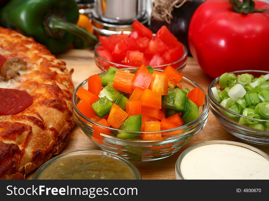 Chopped green and orange bell peppers surrounded by pizza and toppings. Chopped green and orange bell peppers surrounded by pizza and toppings.