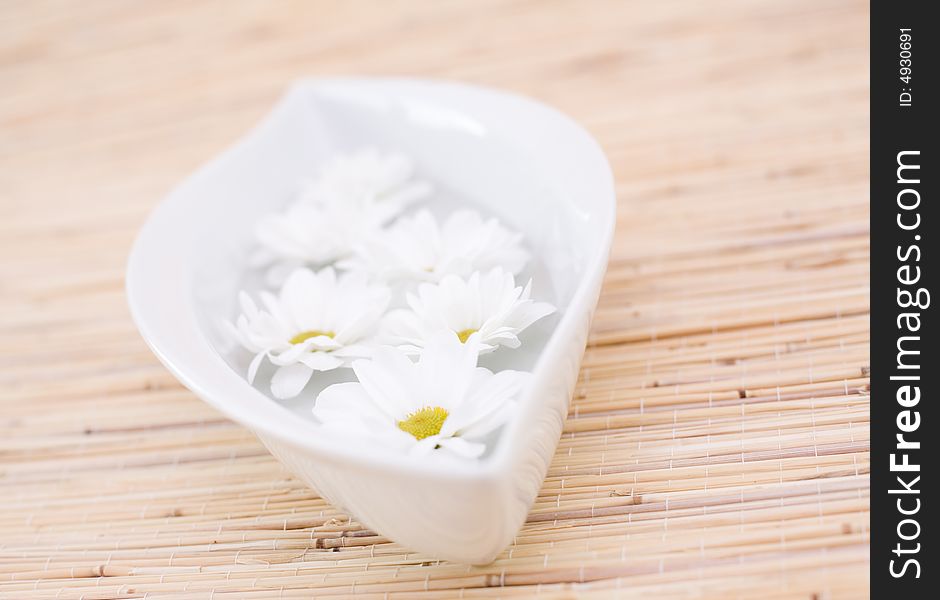 Fresh daisies in the bowl on the bamboo mat. Fresh daisies in the bowl on the bamboo mat