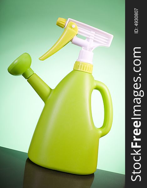Green plastic watering can on the green background