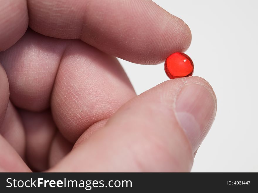 Fingers hold a red pill. Close-up, shallow depth of field. Fingers hold a red pill. Close-up, shallow depth of field.