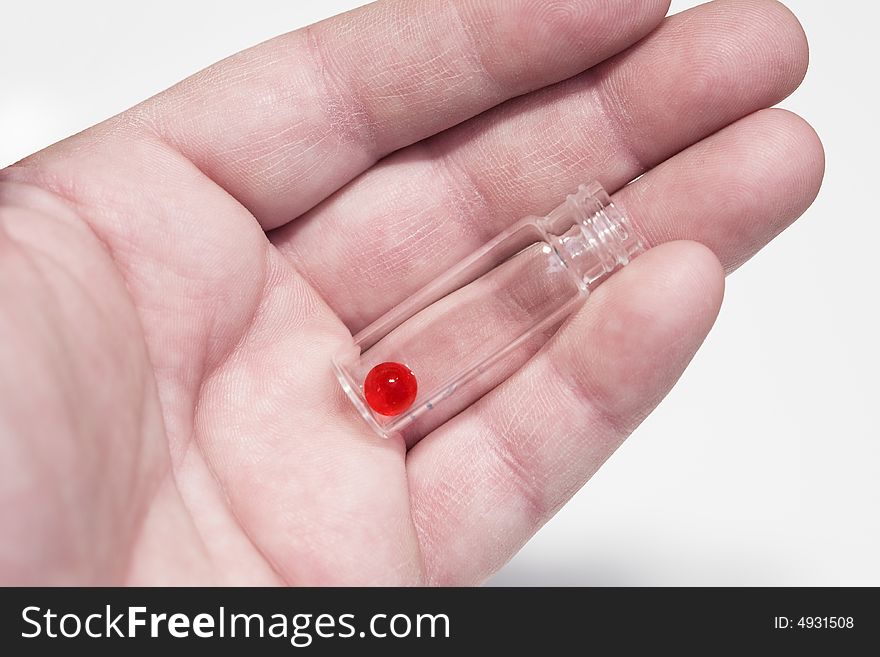 The hand holds the vial with a red pill. Close-up, shallow depth of field. The hand holds the vial with a red pill. Close-up, shallow depth of field.