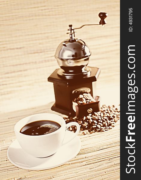 Old-fashioned coffee grinder with coffee beans around it.