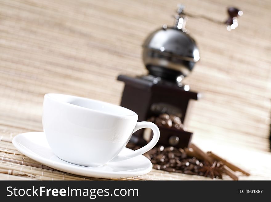 Cup of coffee, grinder and coffee beans on the bamboo mat