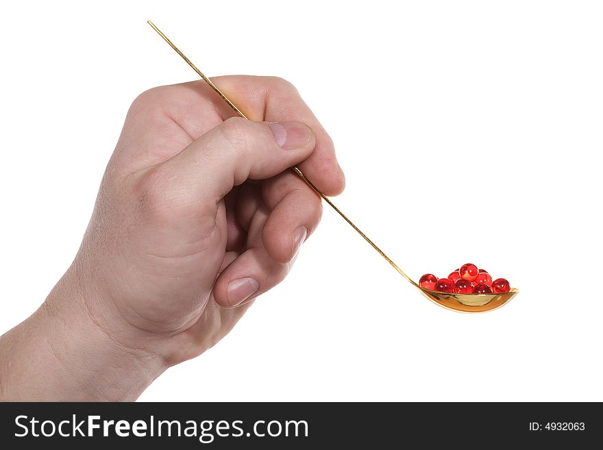 The hand holds a teaspoon with red pills. Isolated on white [with clipping path]. The hand holds a teaspoon with red pills. Isolated on white [with clipping path].