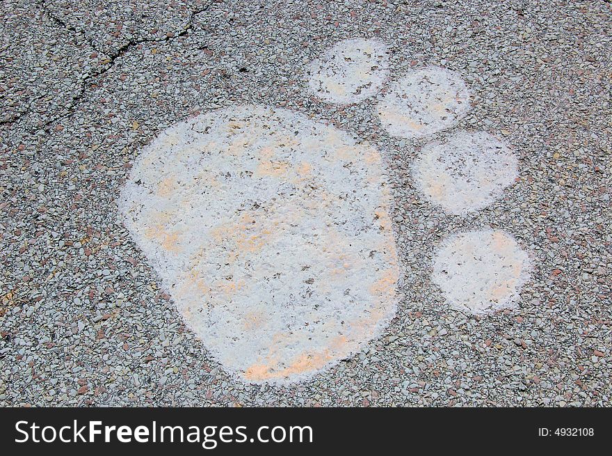 This paw print was painted on the cracking road and is fading away. This paw print was painted on the cracking road and is fading away.