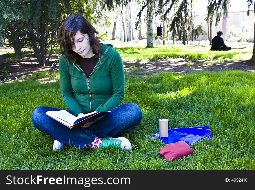 Young student reading on the grass in the park. Young student reading on the grass in the park.