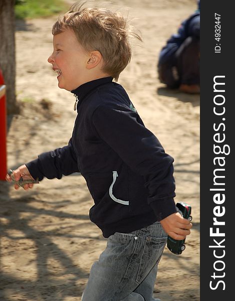 Little boy is running happily around the playground with toys in his hands. Little boy is running happily around the playground with toys in his hands