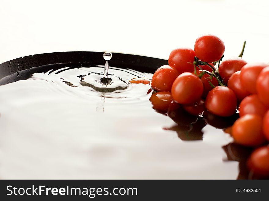 Tomato-cherry in the bowl full of fresh water / drop. Tomato-cherry in the bowl full of fresh water / drop