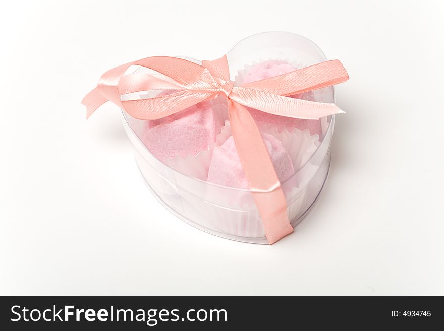 Little pink cakes in a heart shaped box over white background. Originally it's a bath salts look like cakes or sweets.