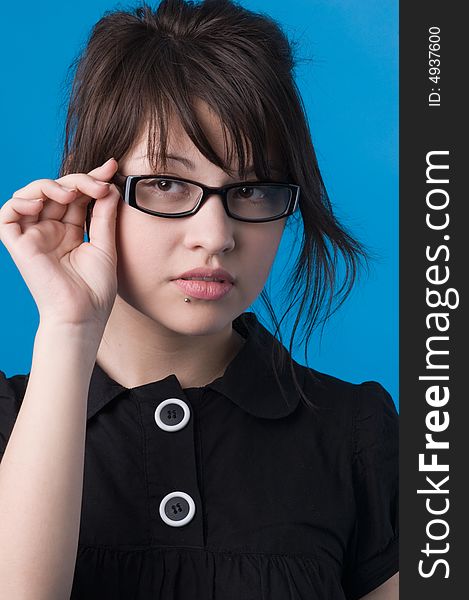 The girl on a dark blue background tries on glasses. The girl on a dark blue background tries on glasses.