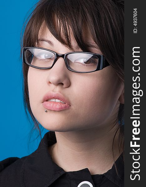 The girl on a dark blue background tries on glasses. The girl on a dark blue background tries on glasses.