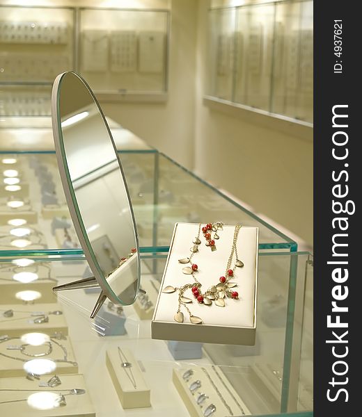 Present gift in jewelry shop. Necklace with red gems near mirror