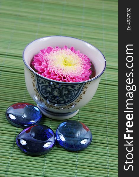 Pink flower in a vase with blue stones.
