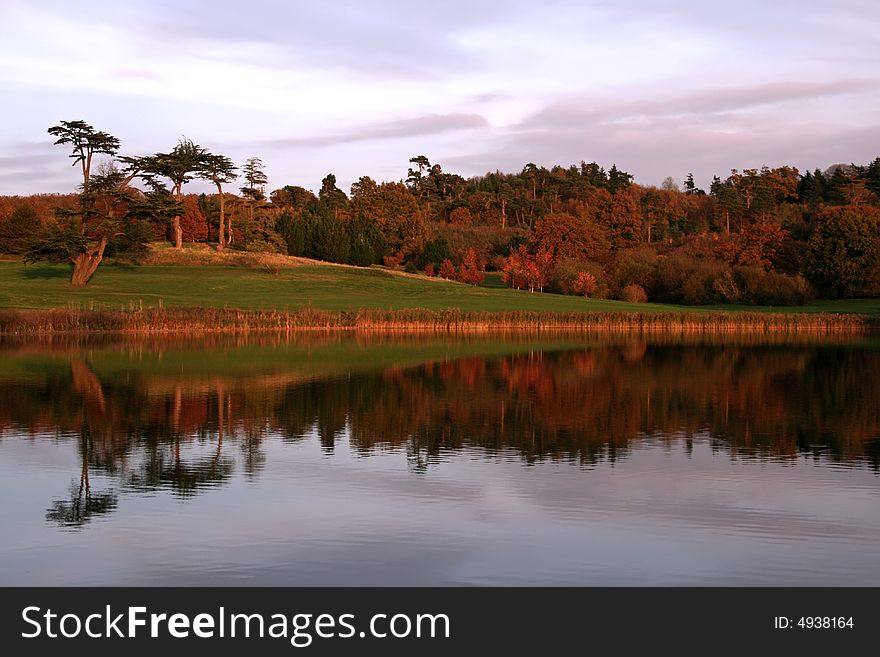 Tree line reflected into lake as the sun sets