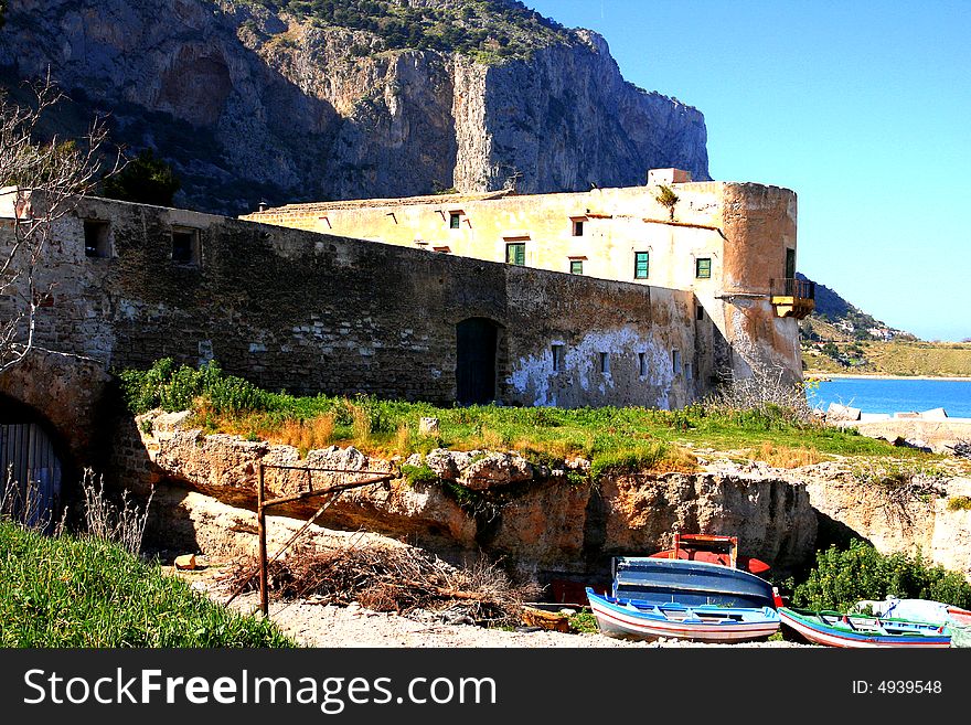 Ancient Tuna fishing construction Tonnara Bordonaro XVI century in Palermo. View on Mount Pellegrino blue sky and sea. Island of Sicily, Italy. Ancient Tuna fishing construction Tonnara Bordonaro XVI century in Palermo. View on Mount Pellegrino blue sky and sea. Island of Sicily, Italy