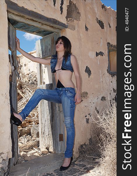Sexy young woman with blue jeans on old house under blue sky. Sexy young woman with blue jeans on old house under blue sky