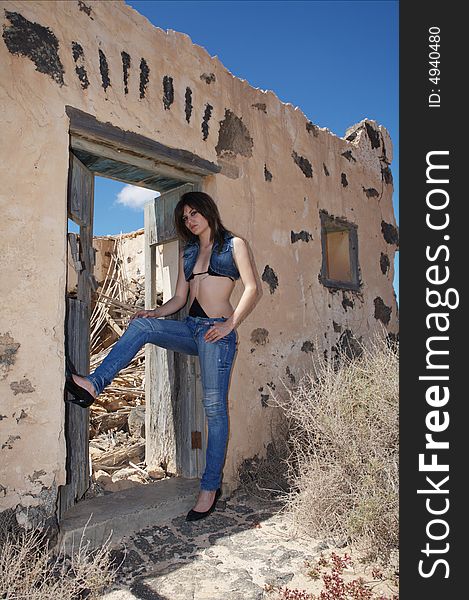 Sexy young woman with blue jeans on old house under blue sky. Sexy young woman with blue jeans on old house under blue sky