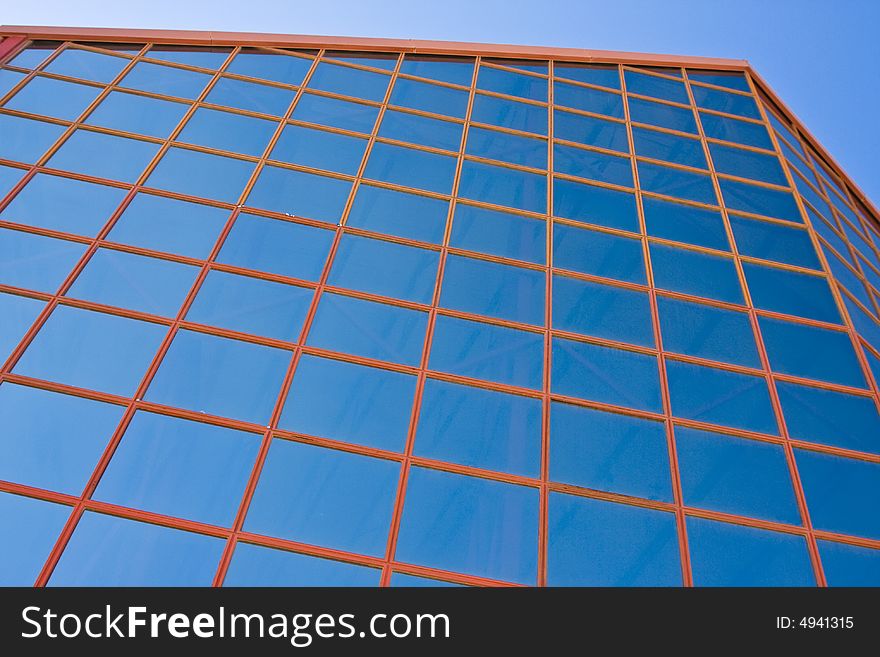 Blue windows from office building against blue sky.