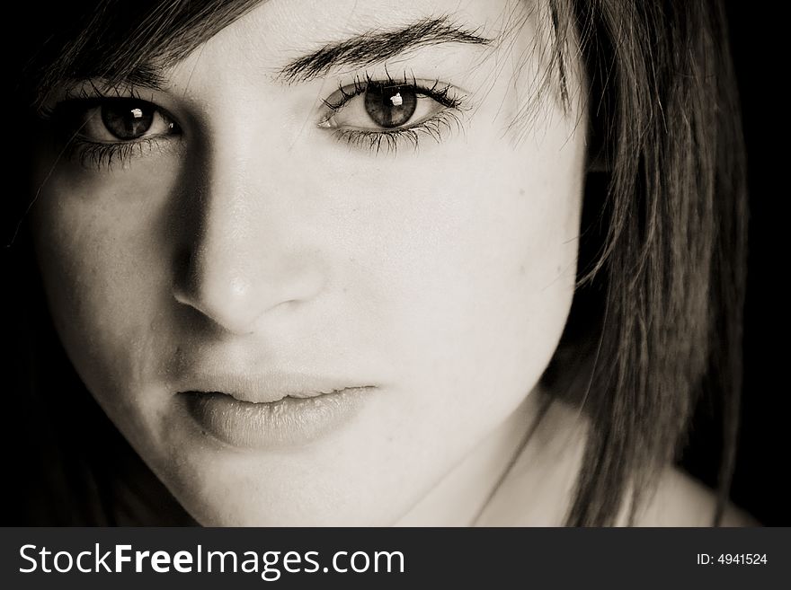 Young woman close portrait in dark sepia.