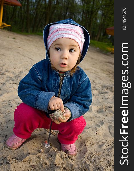 Little girl playing in sand on river back. Little girl playing in sand on river back