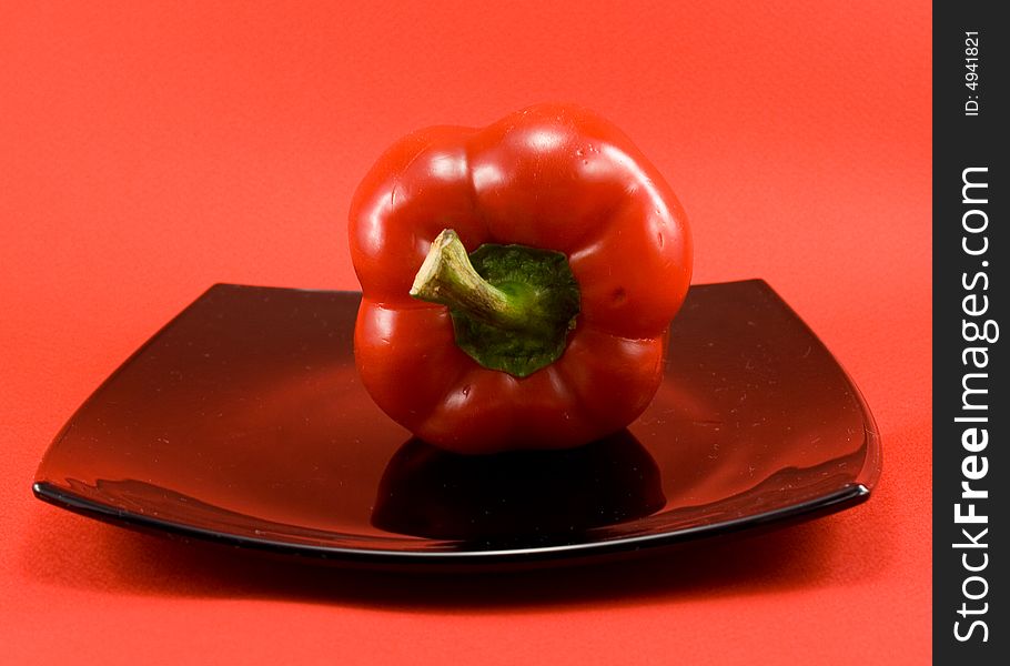 Red pepper on plate on red background