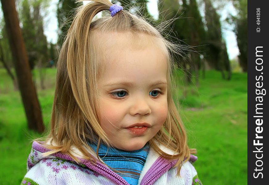 Little girl walks in the spring on a young grass in park