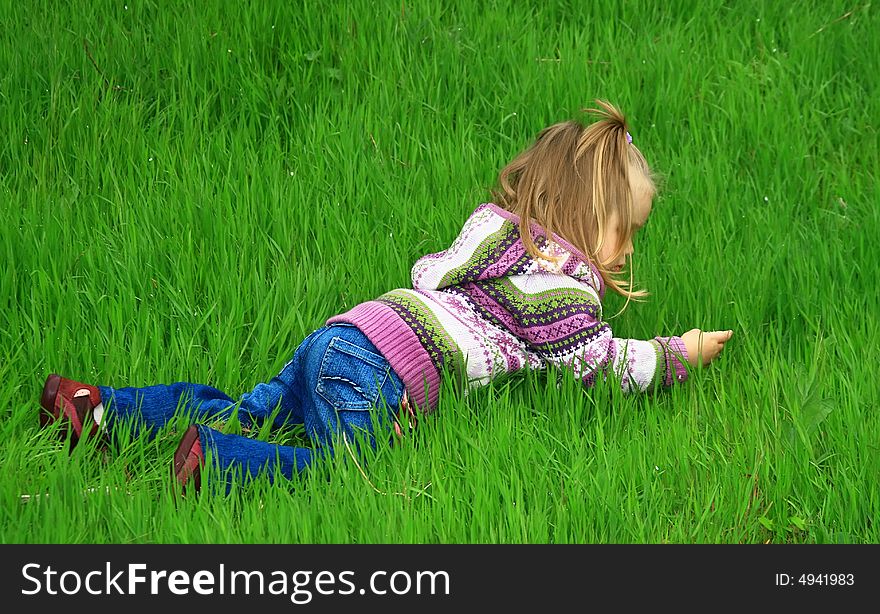 Little girl walks in the spring on a young grass in park