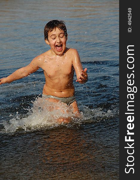 Boy running merrily in water having fun on the beach. Boy running merrily in water having fun on the beach