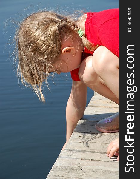 Little girl playing with water on a pier