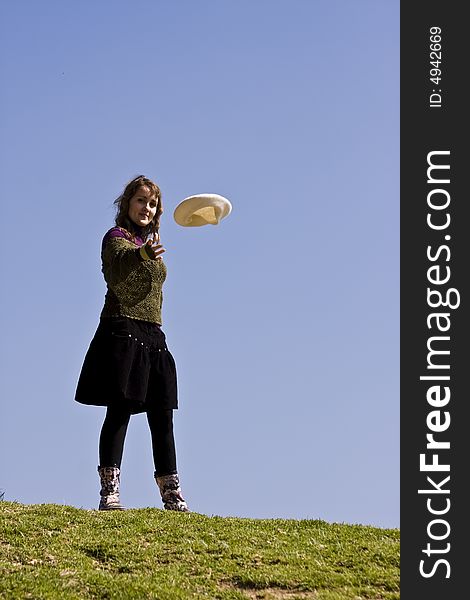 Happy young woman throwing her beret over the grass