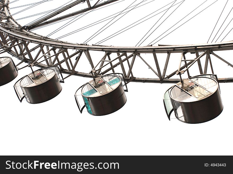 The underslung capsule and steel trusses of a Ferris Wheel in a city amusement park. The underslung capsule and steel trusses of a Ferris Wheel in a city amusement park.