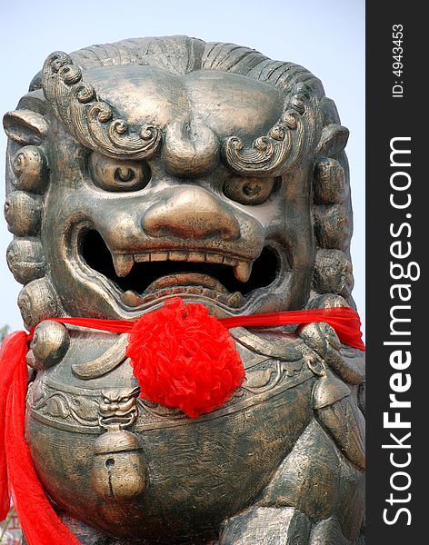 A  chinese bronze lion statue with red ribbon. A  chinese bronze lion statue with red ribbon.