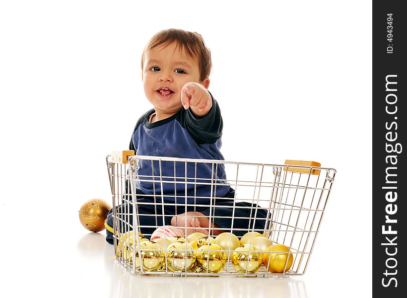 Happy baby boy pointing directly at the viewer from behind a wire basket of gold Christmas bulbs.  Isolated on white. Happy baby boy pointing directly at the viewer from behind a wire basket of gold Christmas bulbs.  Isolated on white.