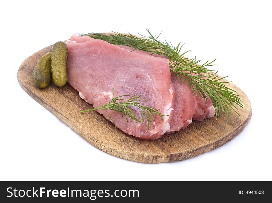 Raw pork schnitzel with pickled cucumbers and dill on a wooden hardboard isolated on white