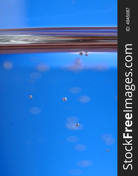 A macro of a glass of water in front of blue background