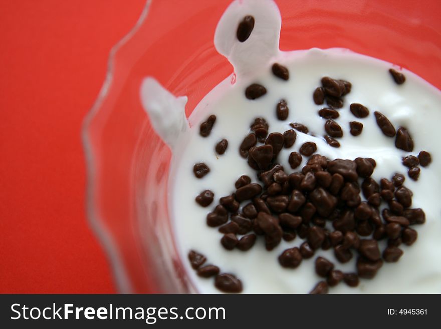 Yogurt (yoghurt) with chocolate in dish on the red background, selective focus